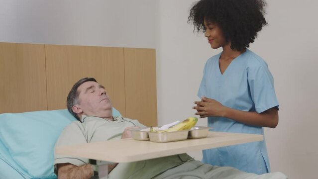 Friendly nurse talking to bedridden patient in hospital