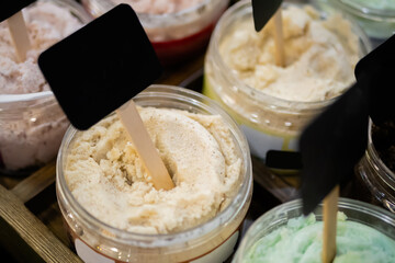 Set of jars with natural body, face scrub with empty price tag on counter of cosmetic store. Treatment, care and wellness concept