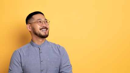 Obraz premium Nice Offer. Smiling Asian Man Looking Aside At Copy Space With Interest