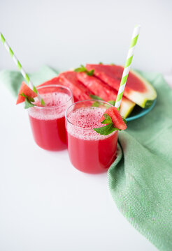 Juicy fresh watermelon juice in a glass along with a green tube, delicious and healthy summer food.