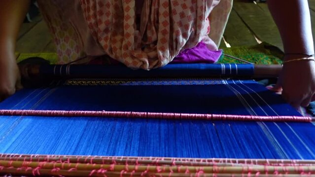 A hilly Chakma tribal woman weaves cloth with a hand-made loom in her own home in the Rangamati district.