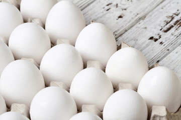 Close-up of Cardboard tray with white chicken eggs on wooden background