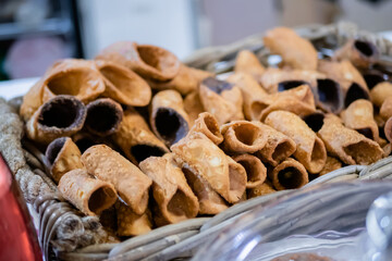 Sweet empty fried cannoli without filling in basket on counter at food market. Pastry, dessert, culinary, italian sweet food and confectionery concept