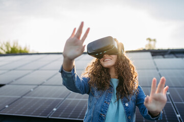 Young woman with virtual goggles on the roof with solar panels.