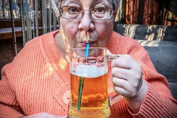 Enjoy delicious fresh beer. Elderly woman drinking beer in a cafe. Kazakhstan, Shymkent - January...