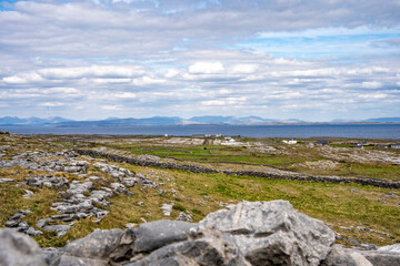 Fototapeta na wymiar Landscape of Inis Mór, or Inishmore, the largest of the Aran Islands in Galway Bay, off the west coast of Ireland, with houses and stone walls.
