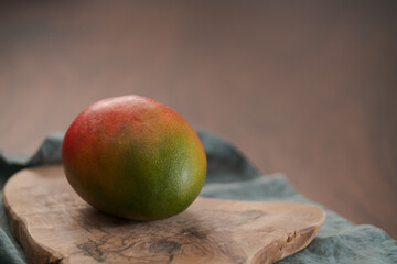 Whole ripe red mango on olive wood board