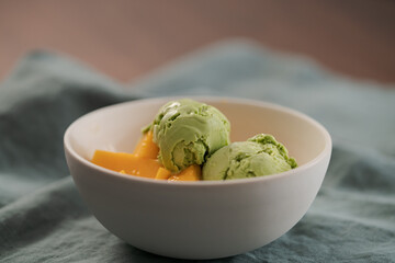 green matcha tea ice cream with fresh mango in white bowl