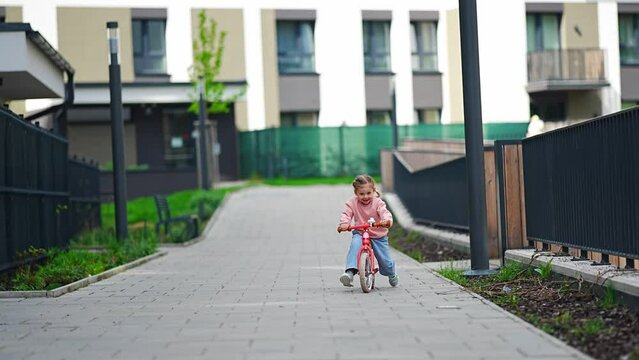 Little girl riding balance bike in the courtyard of the residence in Prague, Europe