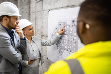 Construction worker and architects having a meeting at construction site analyzing project plan and next phase of building.