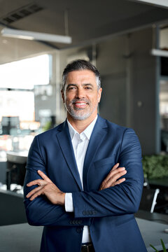 Happy Mid Aged Business Man Ceo Standing In Office Arms Crossed. Smiling Mature Confident Professional Executive Manager, Proud Confident Businessman Leader Wearing Blue Suit, Vertical Portrait.