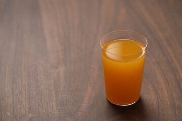 Fresh orange juice in thin glass on wooden table with copy space