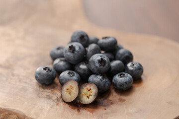 Fresh blueberries on wood board one berry is cut in halves