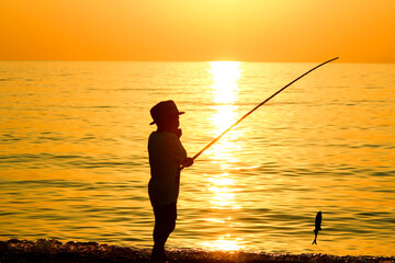 A happy child fishing by the sea silhouette