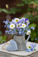 kleiner Blumenstrauß mit lila Hornveilchen, Bellis und Vergissmeinnicht im vintage Krug