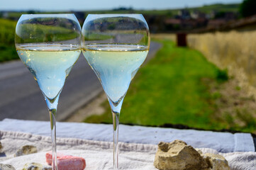 Tasting of grand cru sparkling white wine with bubbles champagne with view on old houses of Oger, small village with grand cru vineyards, France.