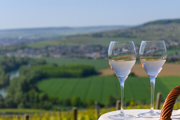 Tasting of premier cru sparkling rose wine with bubbles champagne with view on green pinot noir, meunier vineyards of Hautvillers, France.