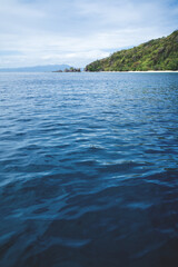 Fototapeta na wymiar Deep blue ocean waves with lush green island and rocks in Palawan, Philippines