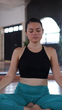 A woman in sportswear sitting on the floor meditating and relaxing at home.