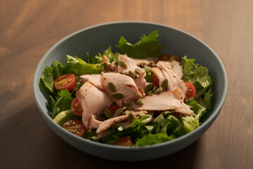 Salad with roasted turkey and cherry tomatoes decorated with pumpkin seeds in blue bowl