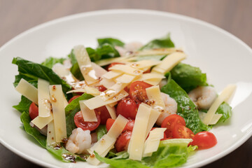 Salad with shrimps, tomatoes and romaine lettuce on white plate