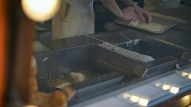 Unrecognizable chef fries chebureks and pies at a fast food point, close-up