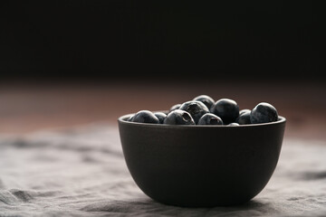 Freshly washed organic blueberries in a black bowl closeup