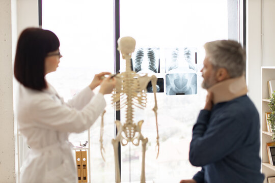 Focus on detailed x-ray pictures of human chest and pelvic bones placed on window panel with adult people talking on blur foreground. Medical imaging test creating radiographs for initial diagnosis.