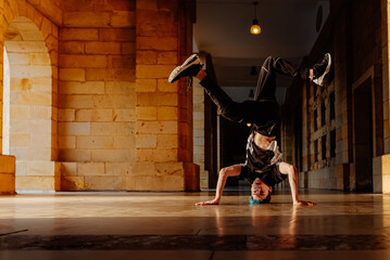 young teenage white boy dances break dance in the old streets of a city. modern dance. b-boy. hip hop culture. youth culture.