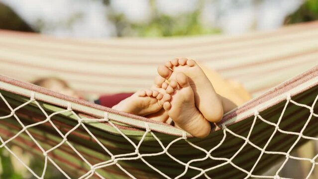 Feet of children, which swinging on hammock at summer.Kids relax,happy childhood