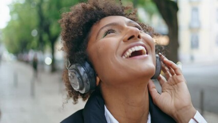 Woman wearing headphones dancing along on city street closeup. Girl in headset
