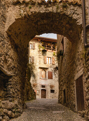 Obraz premium View through an archway into a historical medieval street in Ville del Monte - Italy