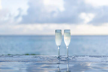 Two glasses of champagne on the side of the infinity pool against the backdrop of a sunset in the Maldives