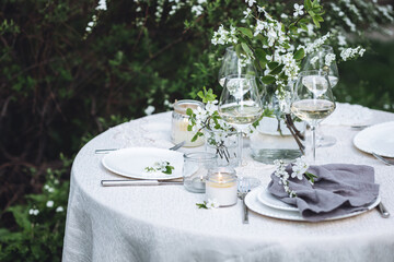 Rustic zero waste wedding decor with natural elements. Fresh spring blooming flowers, candles, linen napkins, wine glasses. Eco friendly decoration for the special holiday dinner. Romantic cozy place