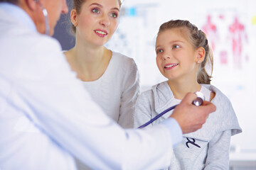Girl and doctor with stethoscope listening to heartbeat - 605035922