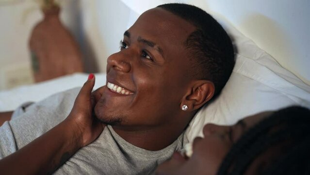 jovem casal negro brasileiro conversando deitados na cama abra&ccedil;ados e se beijando no dia dos namorados