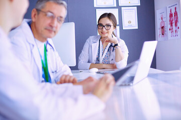 Serious medical team using a laptop in a bright office