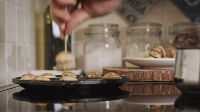 A man making poffertjes at home - buttering up a special pan. Traditional Dutch mini pancakes with buckwheat flour, white flour, egg and milk.