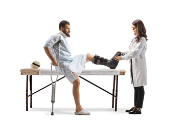 Obraz premium Female doctor putting on a walking brace to a male patient in a hospital gown