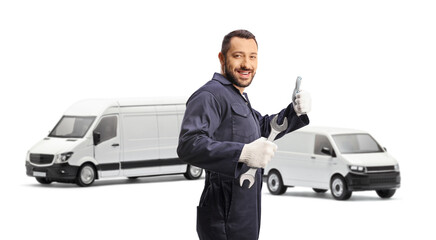 Mechanic holding a wrench and showing a thumb up sign in front of vans