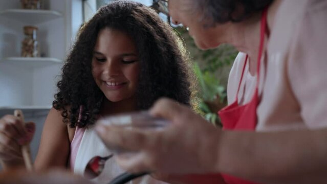 mulher brasileiro na cozinha ensinando sua neta a fazer uma sobremesa para o dia das m&atilde;es