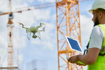 Drone operated by safety engineering inspector. Construction worker piloting drone on building site - 605041323