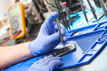 mobile phone repair. Repairman hands with screwdriver opening smartphone