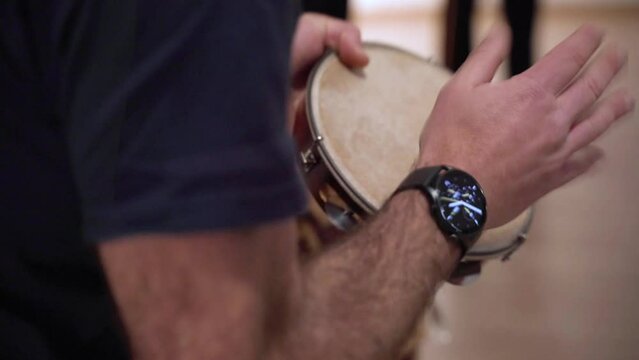 Close-up of a man's hands playing the Brazilian tambourine in a capoeira session
