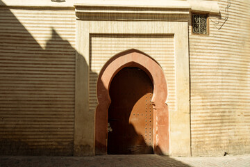 Beautiful moorish arch door entrance with linear pattern walls in the streets of the Marrakech Medina in Morocco