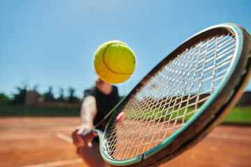 Close up photo of a young girl showing professional tennis skills in a competitive match on a sunny day, surrounded by the modern aesthetics of a tennis court.