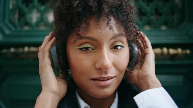Portrait woman wearing headphones outdoors. Girl using earset to listen music.