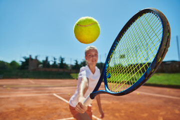 Close up photo of a young girl showing professional tennis skills in a competitive match on a sunny day, surrounded by the modern aesthetics of a tennis court.