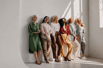 Multi-ethnic group of mature women bonding and smiling while leaning on the wall together