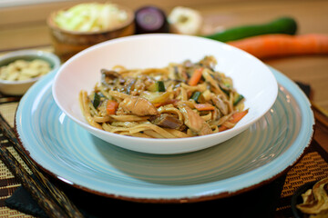Rice noodles served with vegetables and meat in white bowl.